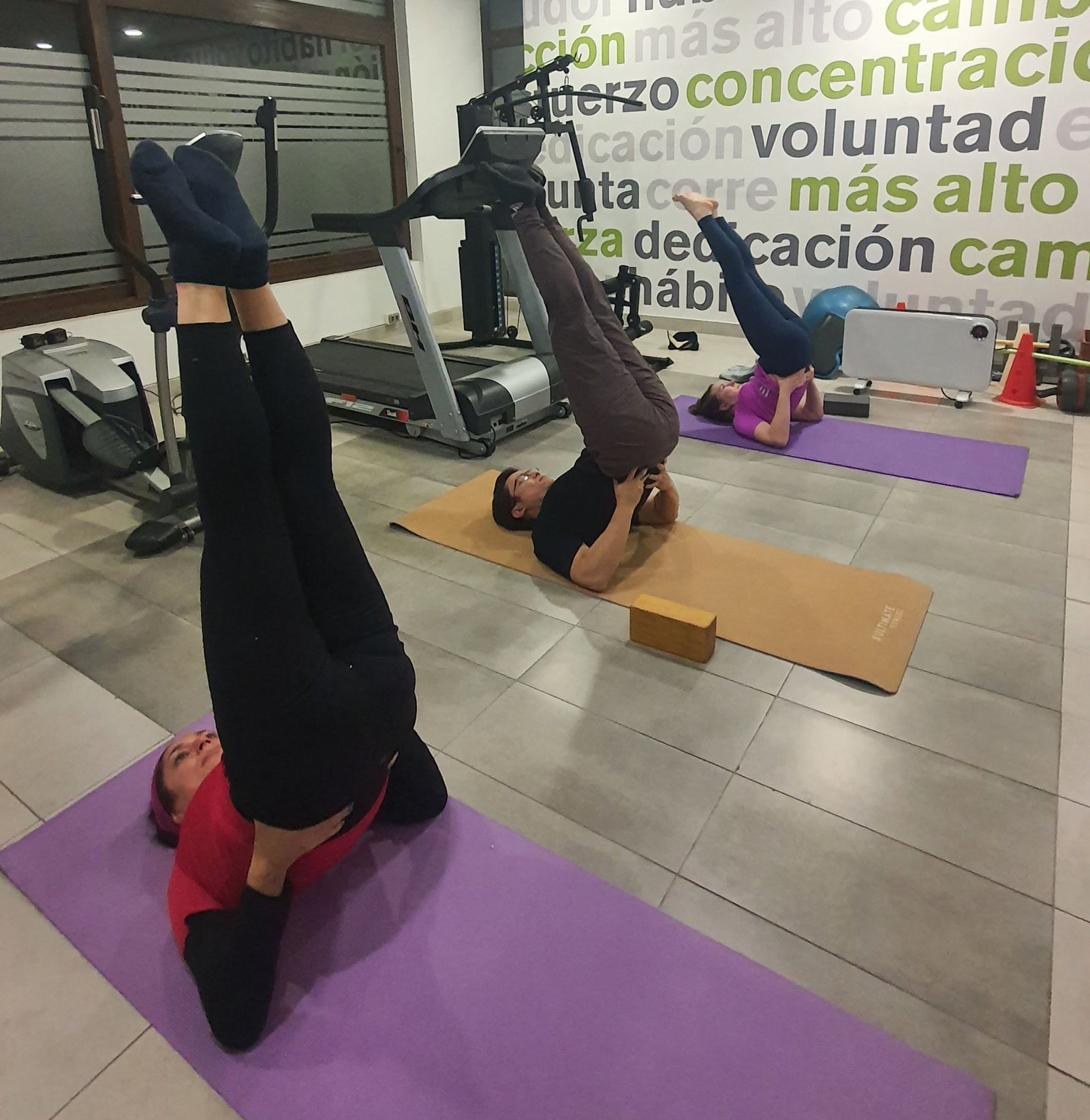 Imagen de una clase de yoga con alumnos haciendo posturas.