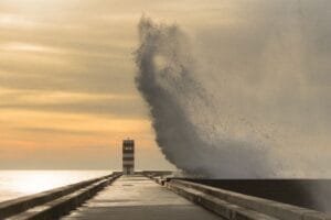 Un ejemplo del instante decisivo: una ola rompe y se eleva sobre un muelle