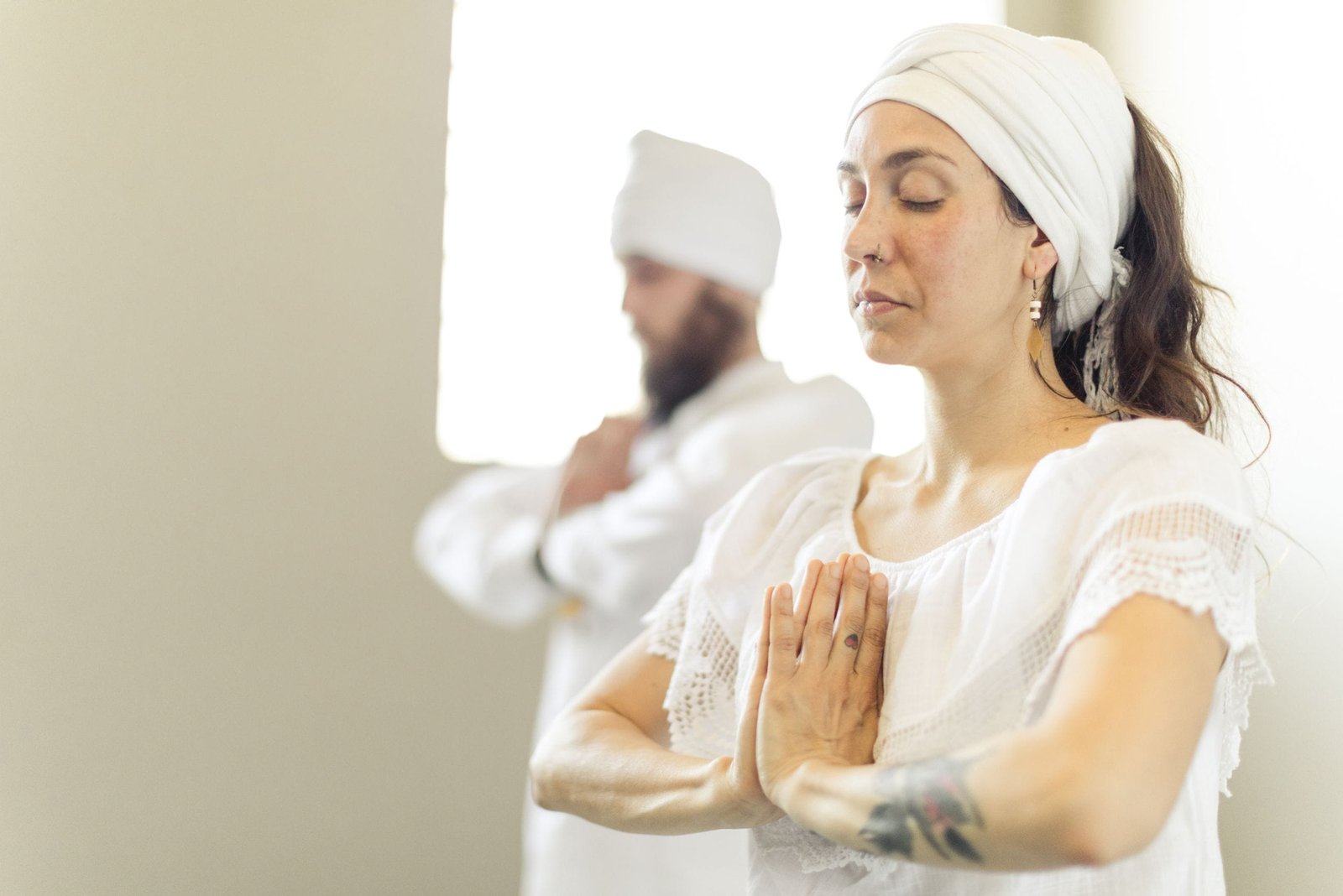 Dos practicantes de kundalini yoga vestidos de blanco con sus manos en anjali mudra