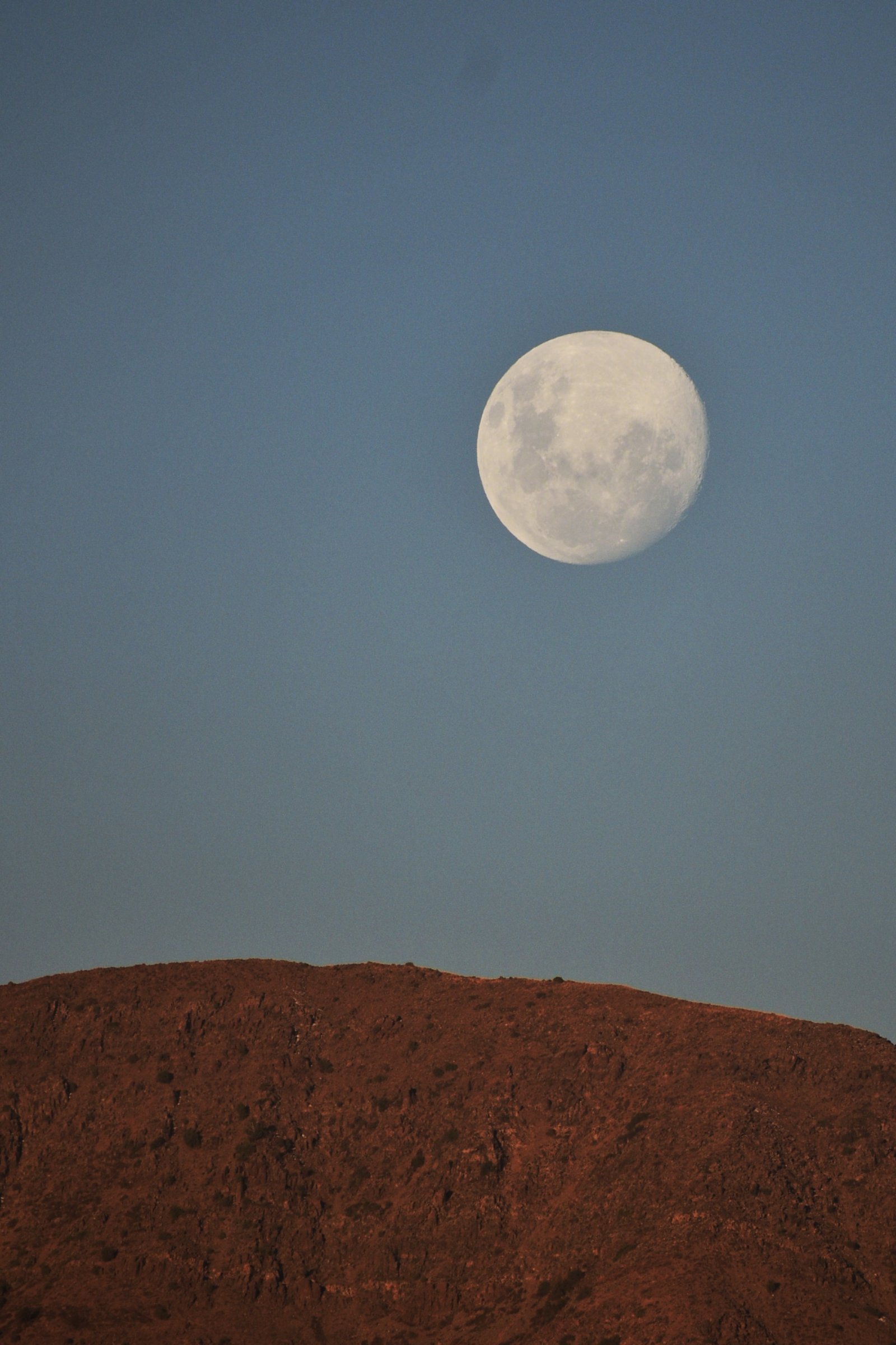 Fotografía de la luna saliendo tras la montaña. 